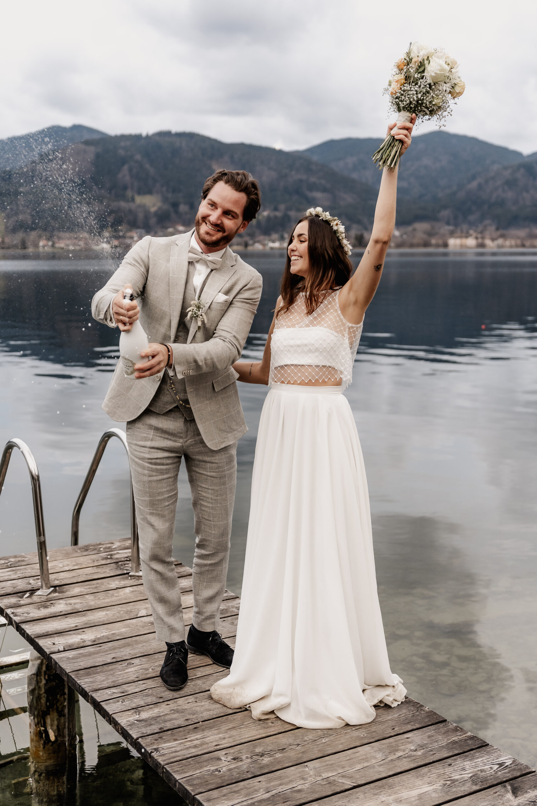 Braut und Bräutigam feiern mit Champagner Flasche am Tegernsee