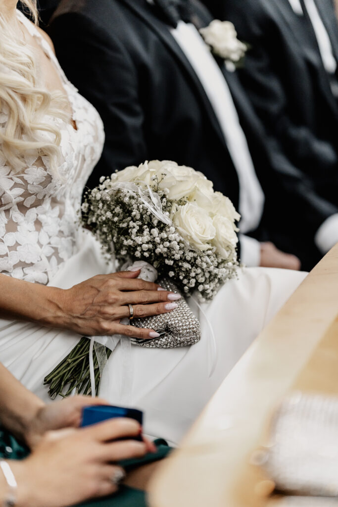 Die Braut hält ihren weißen Brautstrauß auf dem Schoß – Standesamt Aschaffenburg, fotografiert von Hochzeitsfotograf Aschaffenburg.
