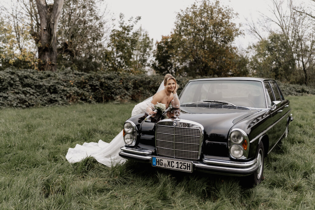 Braut lehnt träumerisch an einem schwarzen Mercedes-Oldtimer, Hochzeitsfotograf Frankfurt