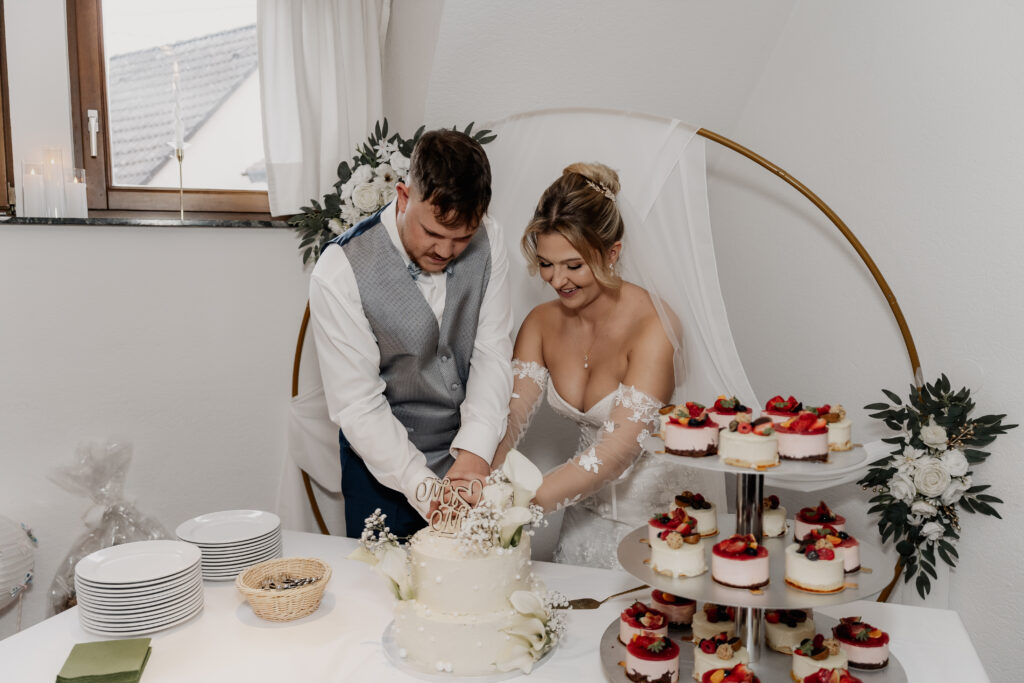 Braut und Bräutigam schneiden glücklich die Hochzeitstorte an im Restaurant Mönchshof Eddersheim