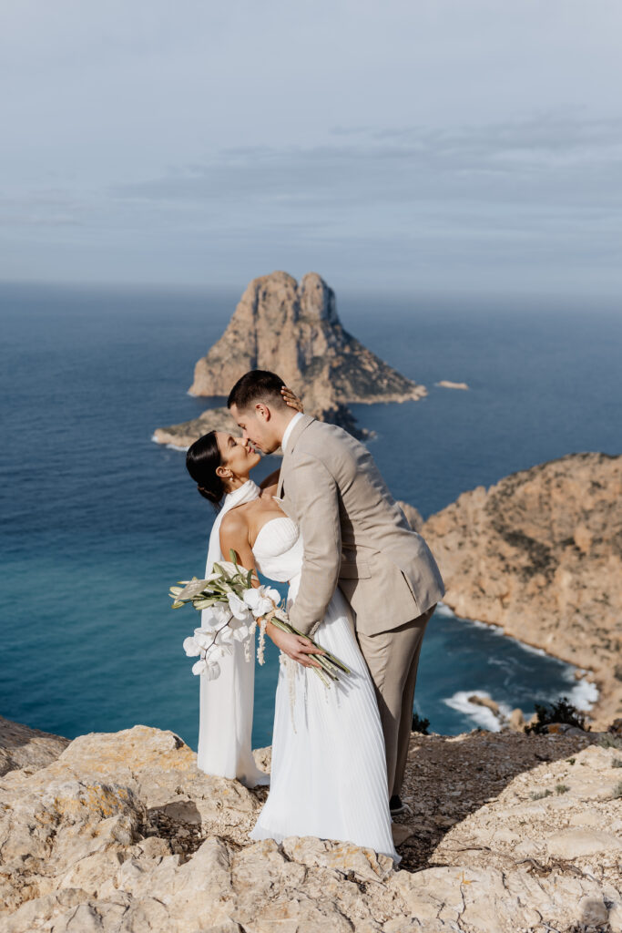 Brautpaar küsst sich vor Klippen – festgehalten von Ibiza Elopement Photographer