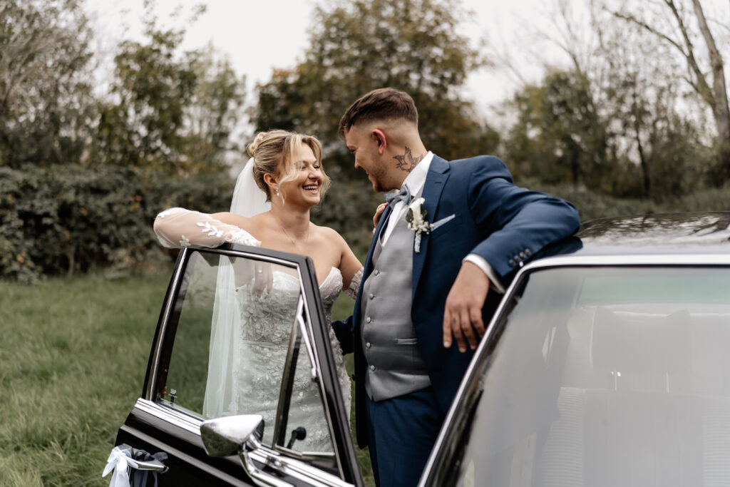 Brautpaar lacht verliebt am Hochzeitsauto, Hochzeitsfotograf Frankfurt