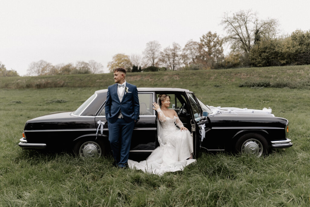 Brautpaar mit Oldtimer auf Wiese. Hochzeitsfotograf Frankfurt