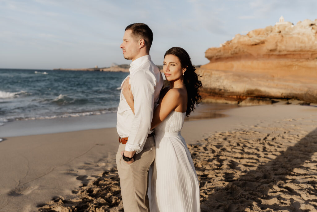 Brautpaar posiert elegant am Felsenstrand – Destination Wedding Photographer