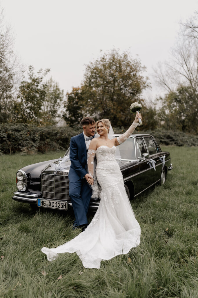 Brautpaar posiert vor geschmücktem Oldtimer dokumentiert von Hochzeitsfotograf Frankfurt