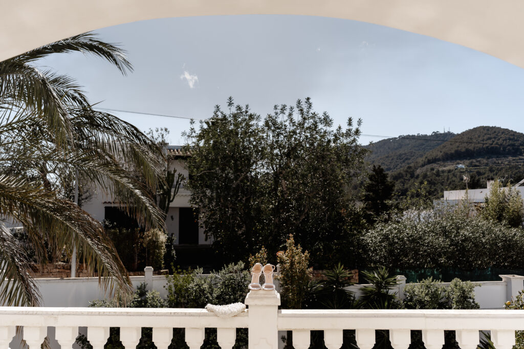 Brautschuhe und Perlen-Tasche auf Brüstung mit Ausblick – Ibiza Elopement Photographer Moment