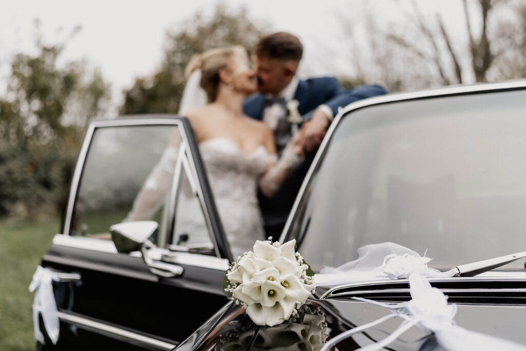 Brautstrauß auf Oldtimer, Brautpaar unscharf. Hochzeitsfotograf Frankfurt