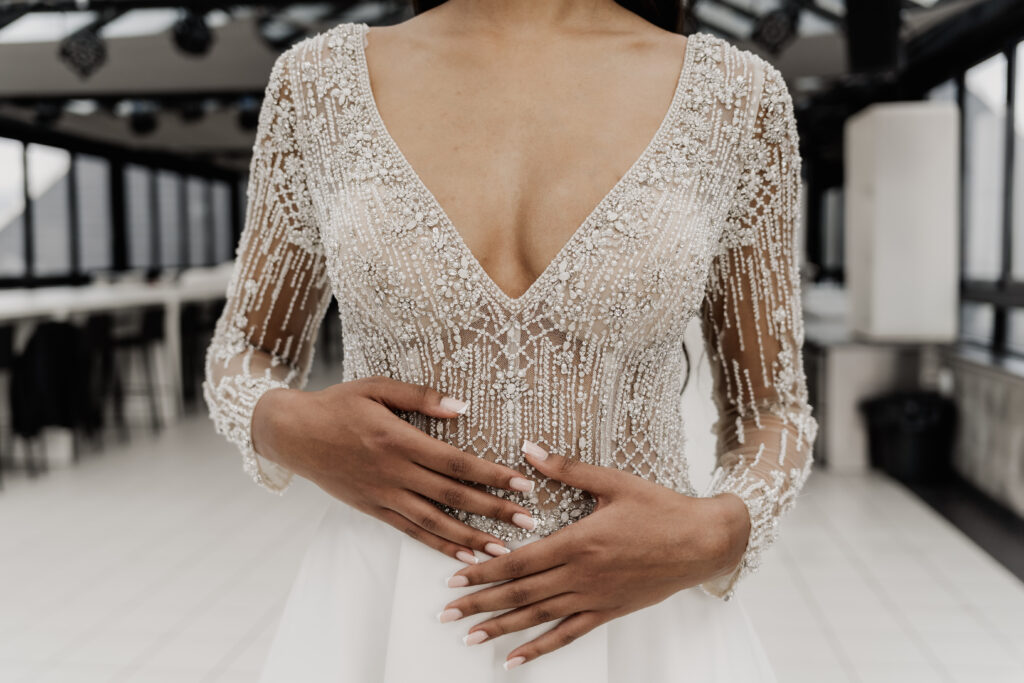 Edles Detailbild vom Brautkleid, Braut streicht mit Fingern über Kleid