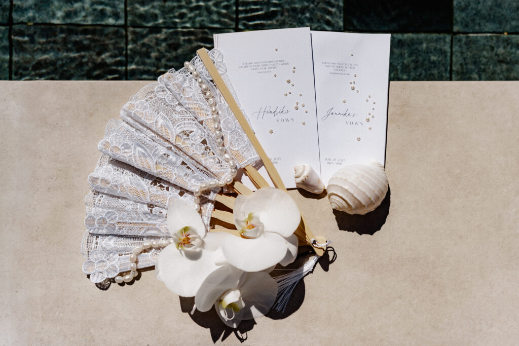Hochzeitsdetails mit Fächer, weißen Orchideen und Vows-Heften – mediterrane Accessoires für eine Elopement auf Ibiza