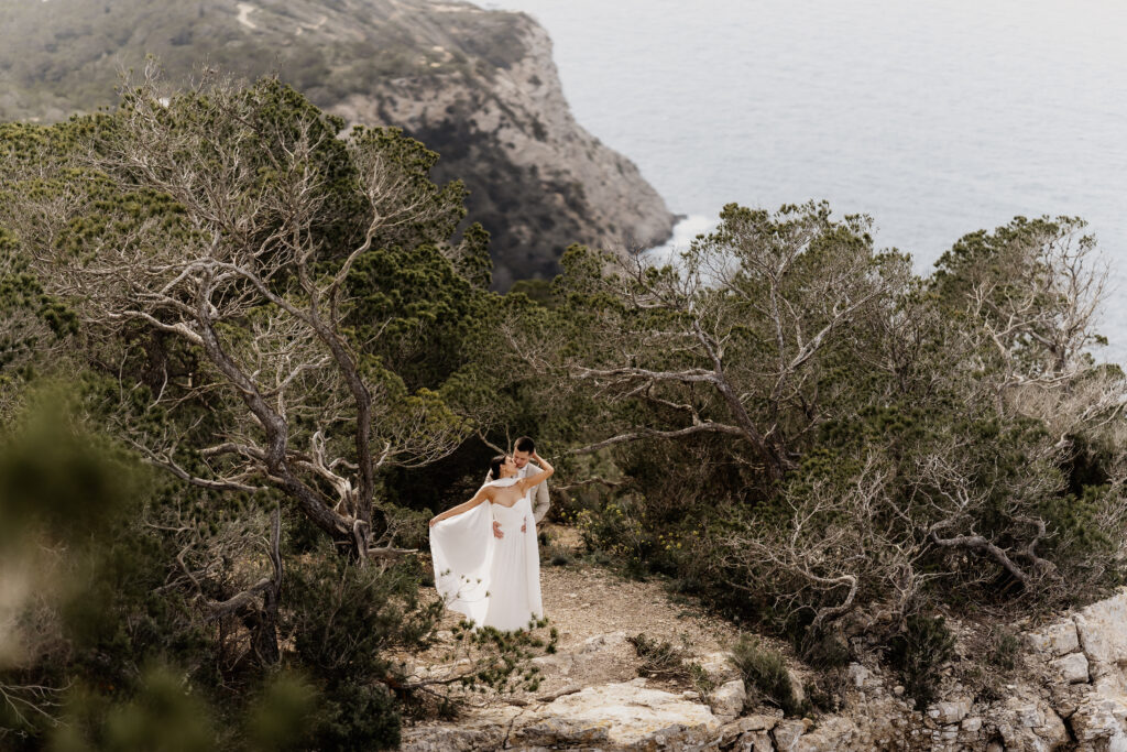 Kuss des Brautpaars vor dramatischer Felskulisse – Destination Wedding auf Ibiza von Ibiza Wedding Photographer Nici