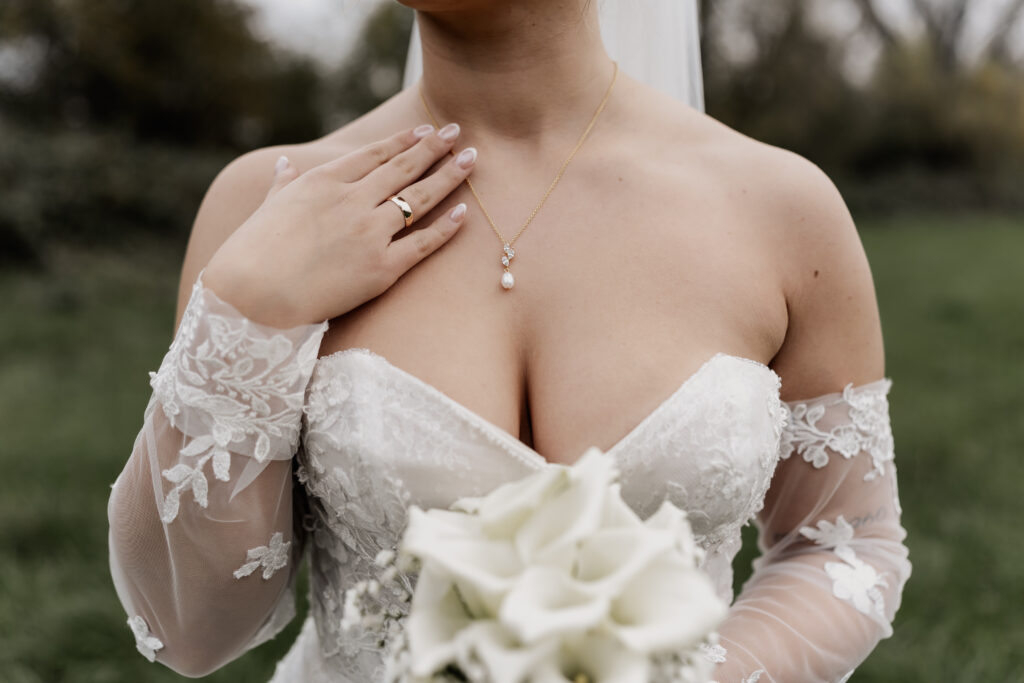 Zarte Spitze am Brautkleid in Nahaufnahme. Schmuckdetails. Hochzeitsfotograf Frankfurt – elegante Hochzeitsdetails.