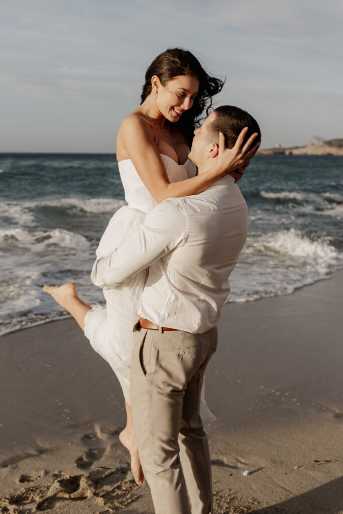 Romantischer Moment am Meer, Braut schaut lachend zu ihrem Partner – Ibiza Elopement Photographer