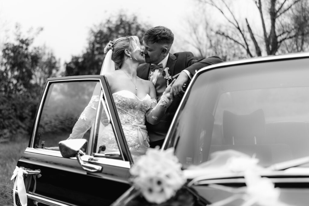 Schwarz-weiß Bild, Kuss am Oldtimer. Hochzeitsfotograf Frankfurt, Hochzeit im Restaurant Mönchshof Eddersheim