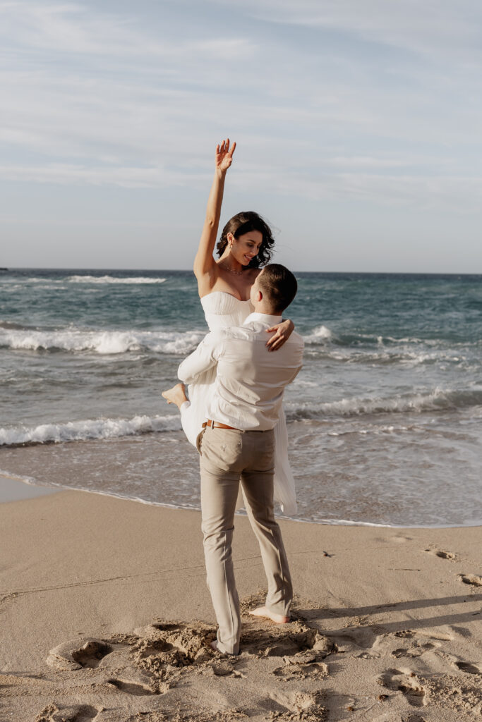 Verliebtes Paar am Meer, Braut hebt Arm in die Luft – Ibiza Elopement Photographer beim Sunsetshooting