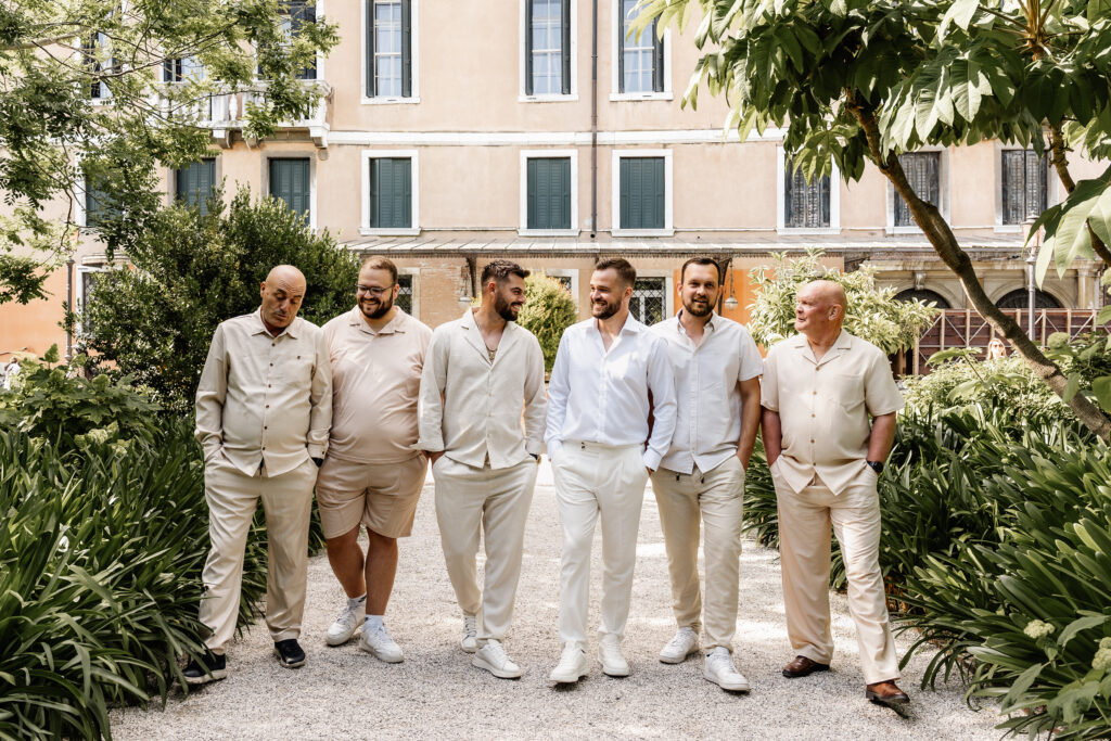 Männergruppe des Bräutigams läuft lachend den Weg im Giardini Reali entlang