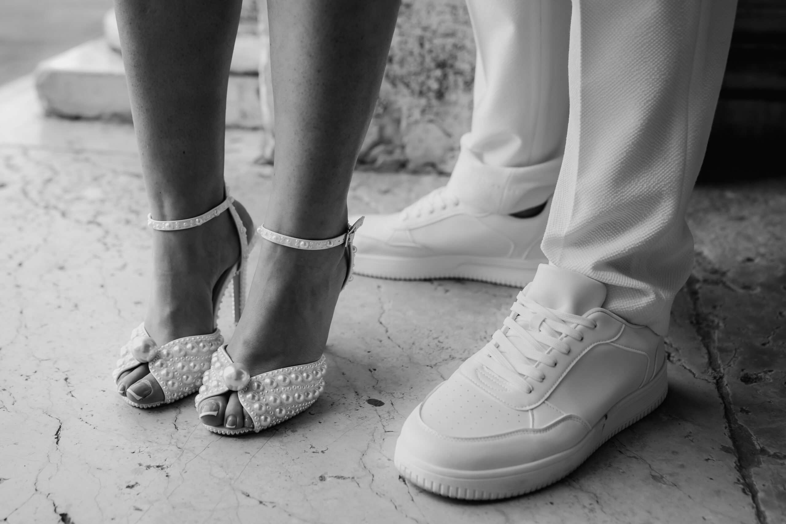 Schwarz-Weiß-Detailbild von Brautschuhen und Schuhen des Bräutigams beim Markusdom Venedig