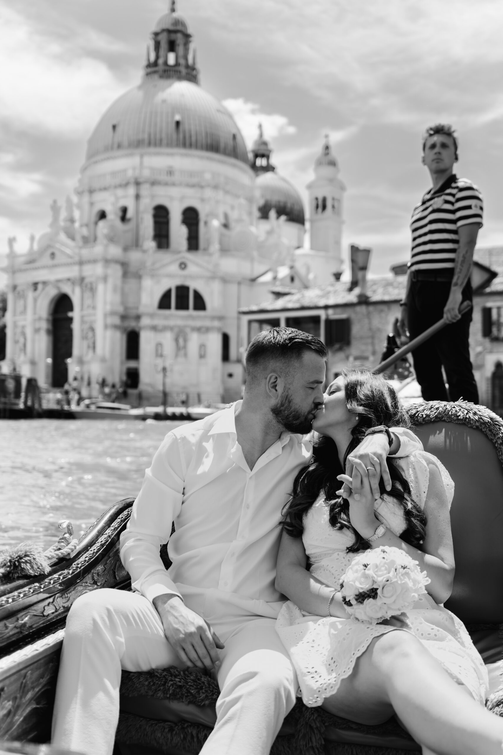Schwarz-Weiß Bild von Brautpaar, sitzend in der Gondel auf Venedigs Kanälen, Dogenpalast im Hintergrund, Hochzeitsfotograf Venedig