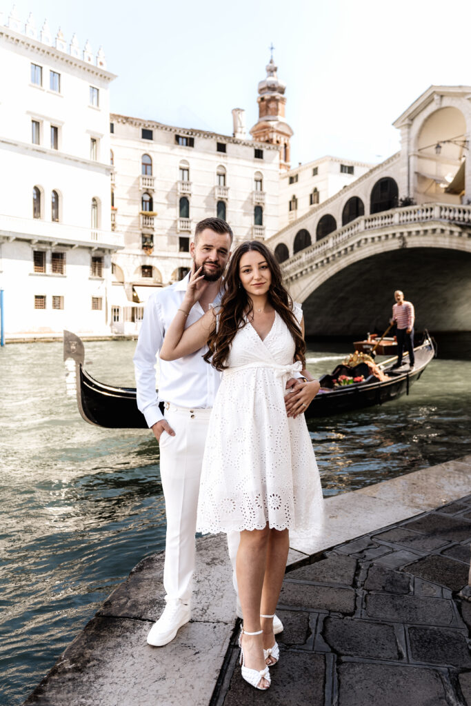 Brautpaar steht vor der Rialto Brücke in Venedig und schaut in die Kamera