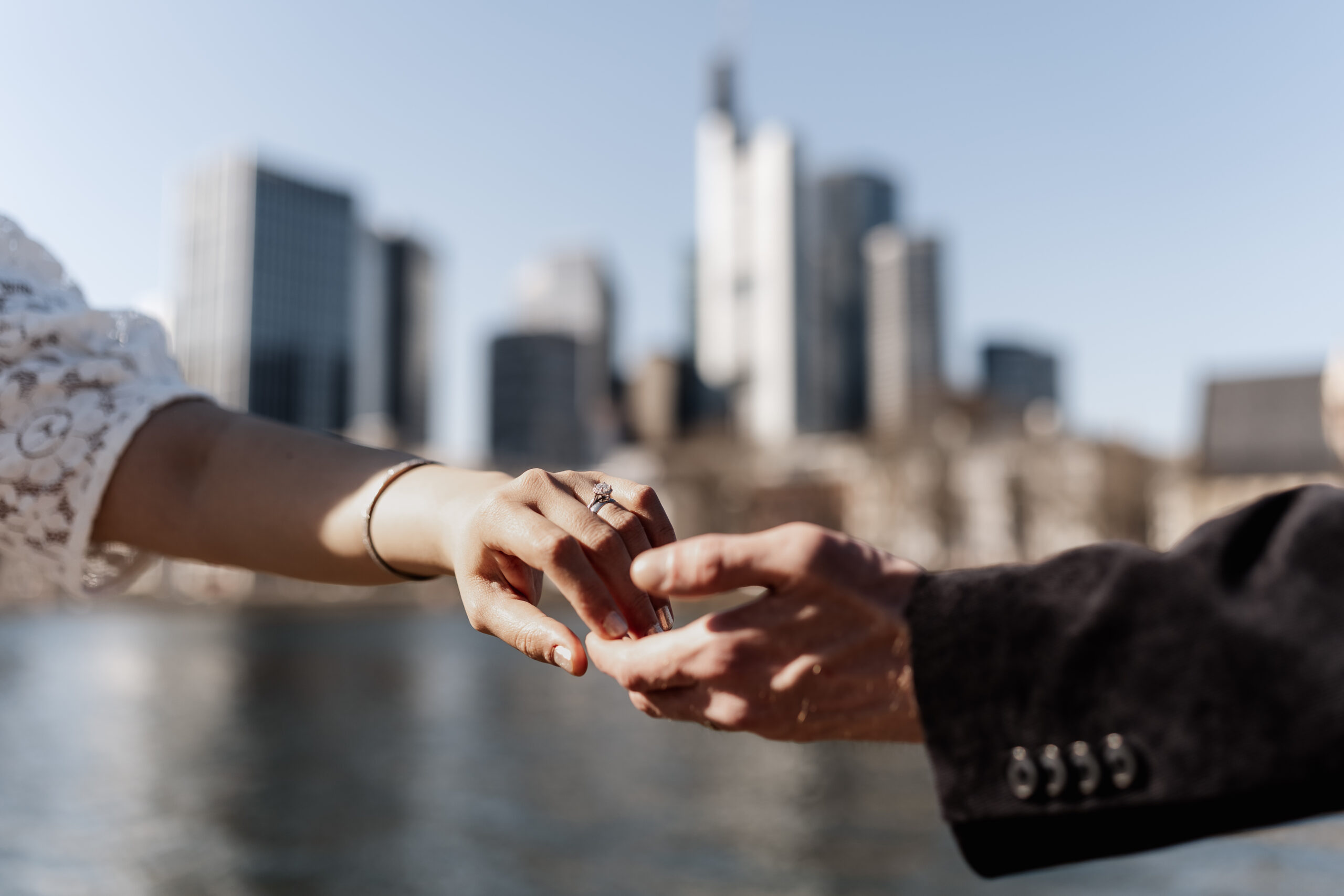 Fokus auf den Händen des Brautpaars, die Frankfurter Skyline verschwommen im Hintergrund