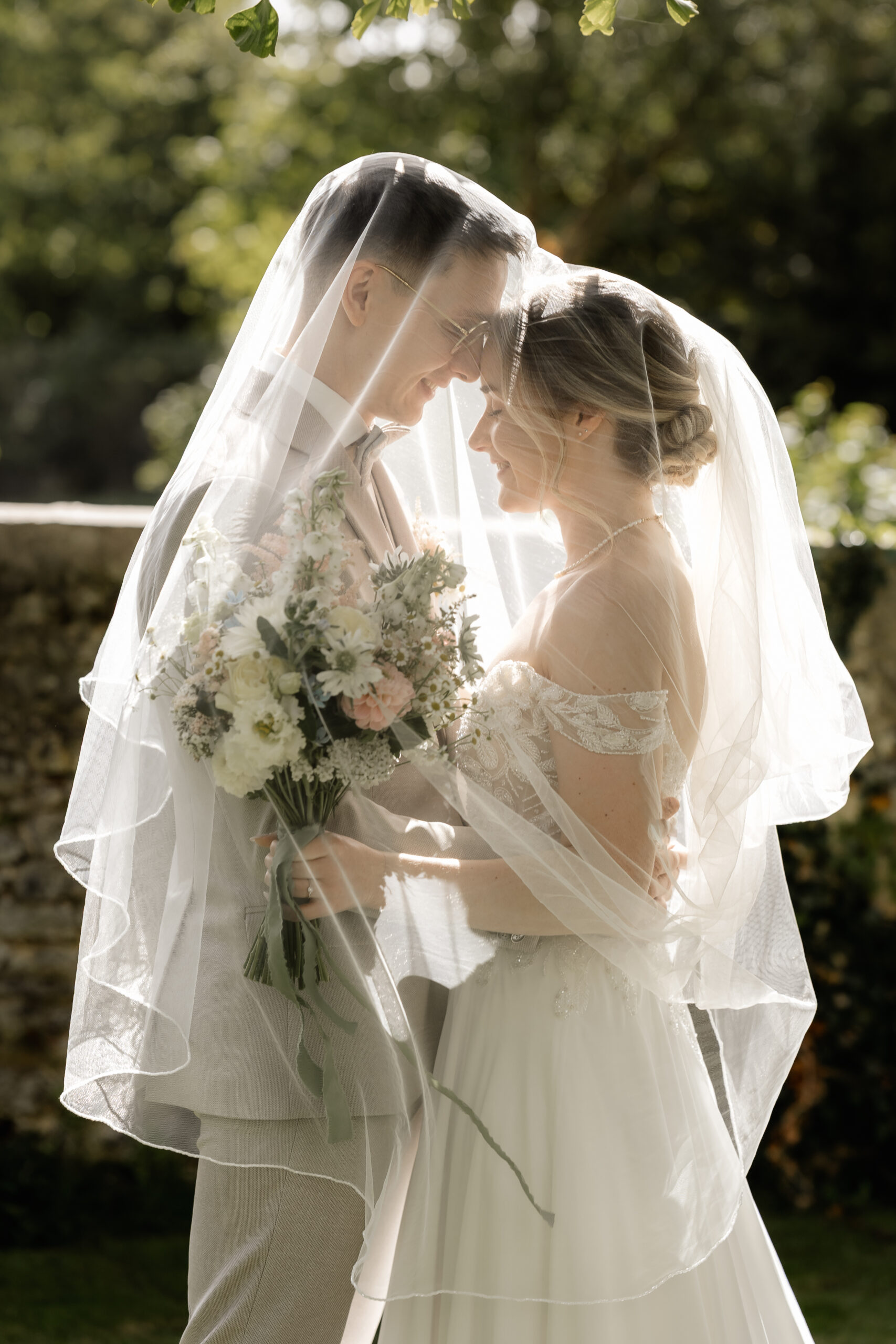 Braut und Bräutigam unter dem Schleier im Gegenlicht, romantisches Paarshooting