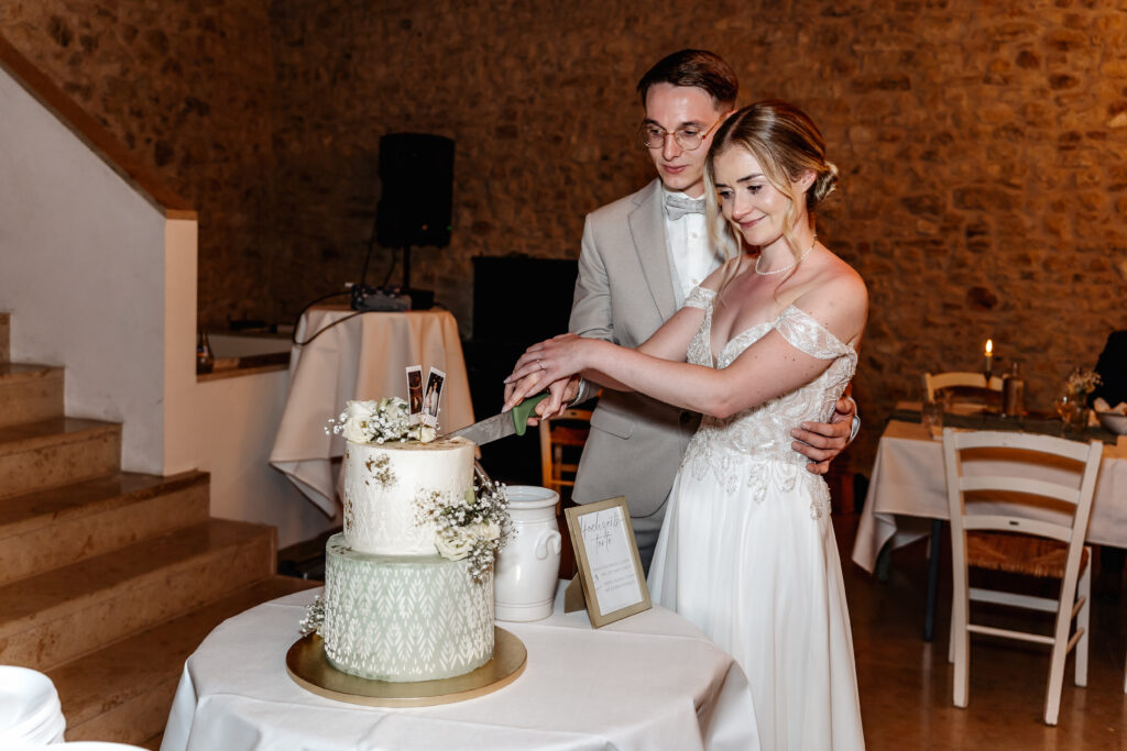 Brautpaar schneidet gemeinsam die Hochzeitstorte im rustikalen Festsaal des Bourdierkellers in Stetten