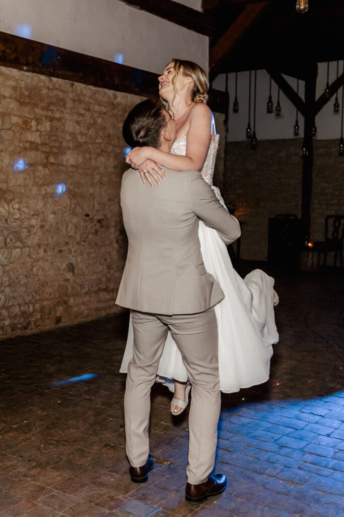 Bräutigam hebt die lachende Braut beim Hochzeitstanz auf der Tanzfläche