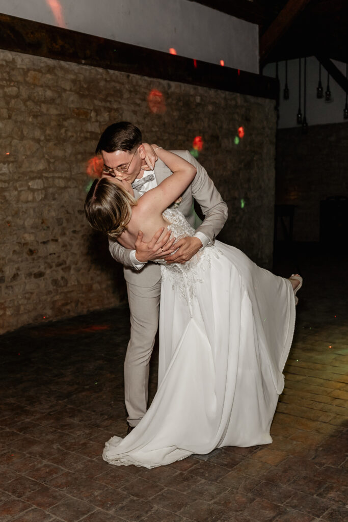 Kuss beim Hochzeitstanz, Braut liegt im Arm des Bräutigams vor Steinwand