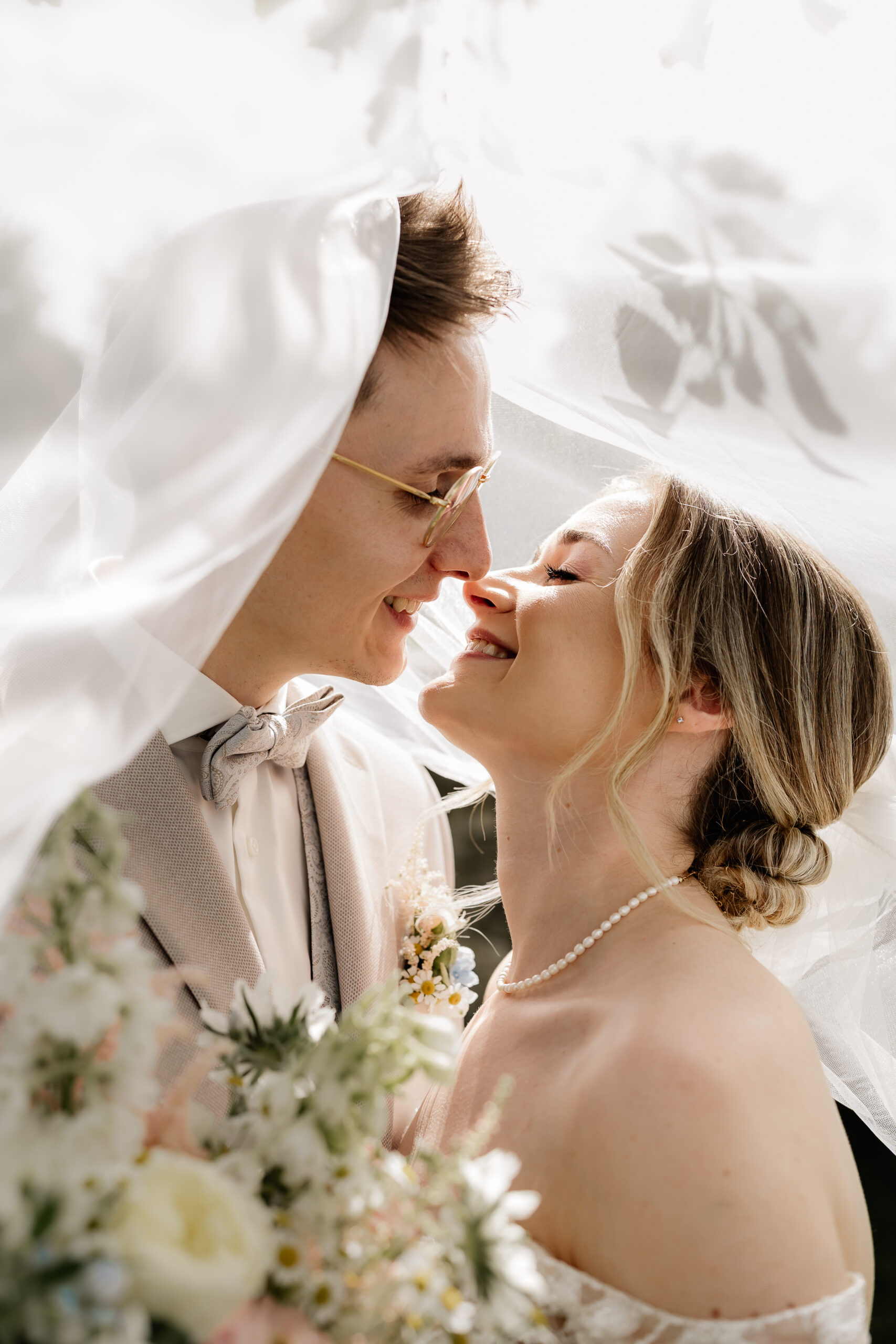 Nahaufnahme vom Brautpaar unter dem Schleier, intime Hochzeitsfotografie