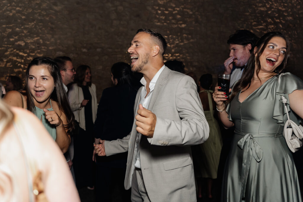 Gäste tanzen ausgelassen unter buntem Licht, lebendige Hochzeitsfeier im Festsaal