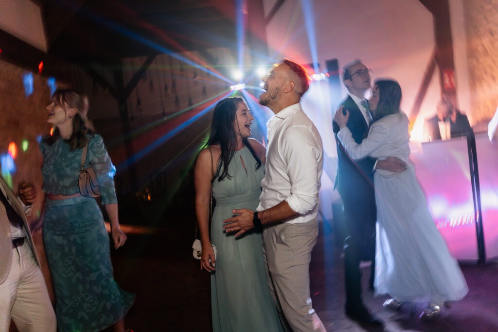 Volle Tanzfläche mit Hochzeitsgästen, farbige Lichteffekte und ausgelassene Partystimmung