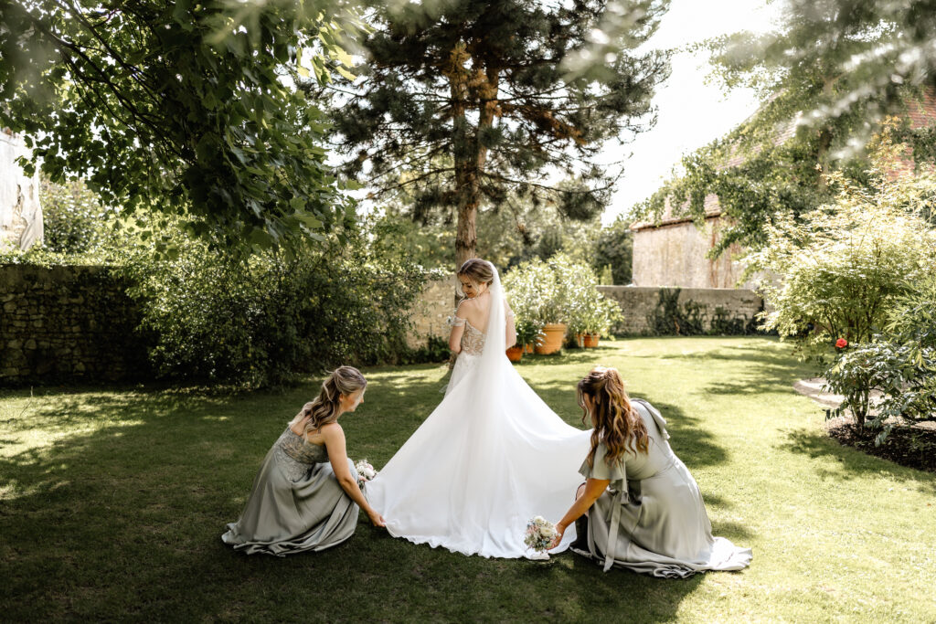 Brautjungfern richten das Brautkleid der Braut