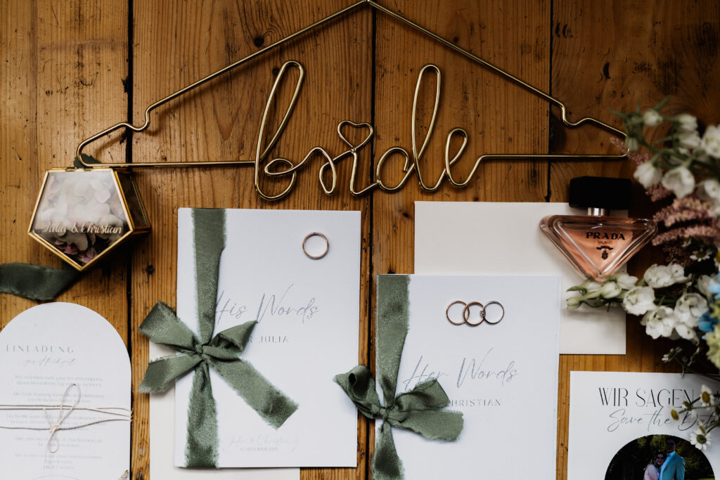 Detail der Hochzeitspapeterie mit Ringen und Schleife, elegante Hochzeitsdetails auf Holzboden
