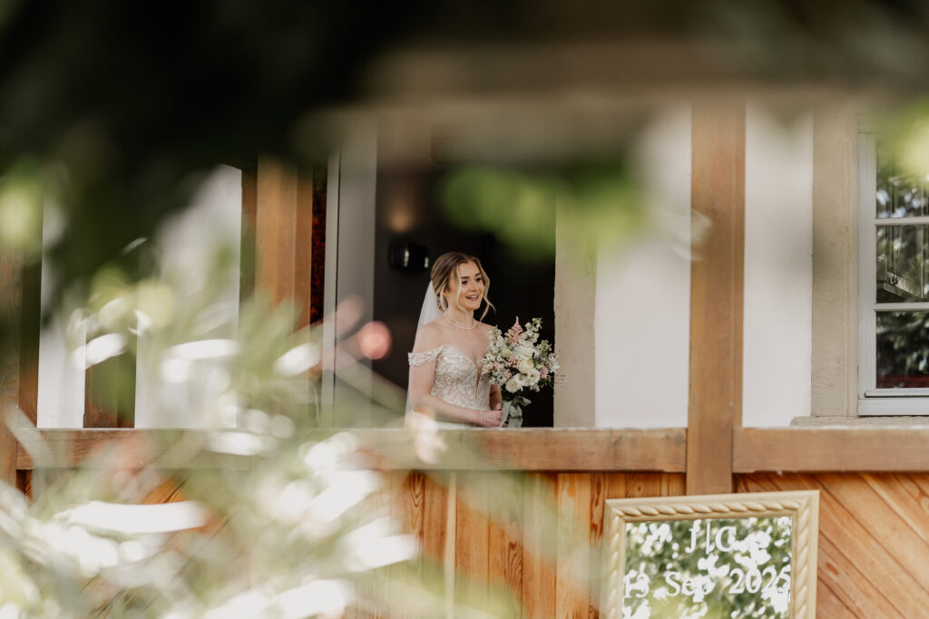 Braut steht mit Brautstrauß auf dem Balkon, emotionale Einlauf zur Trauung