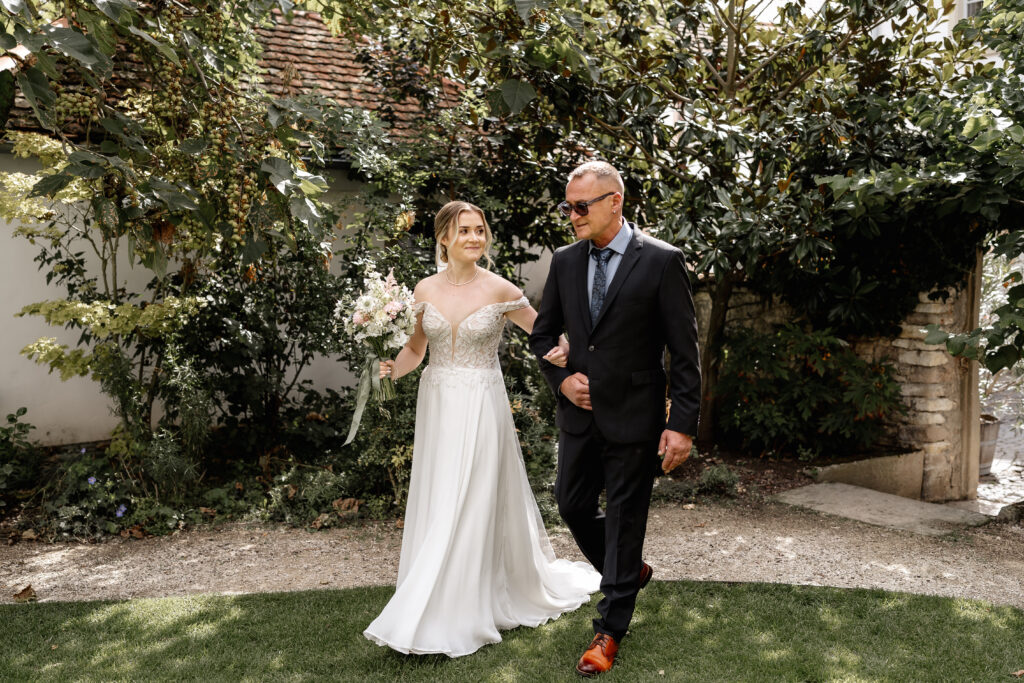 Braut wird von ihrem Vater zur freien Trauung geführt, emotionaler Einzug im Garten