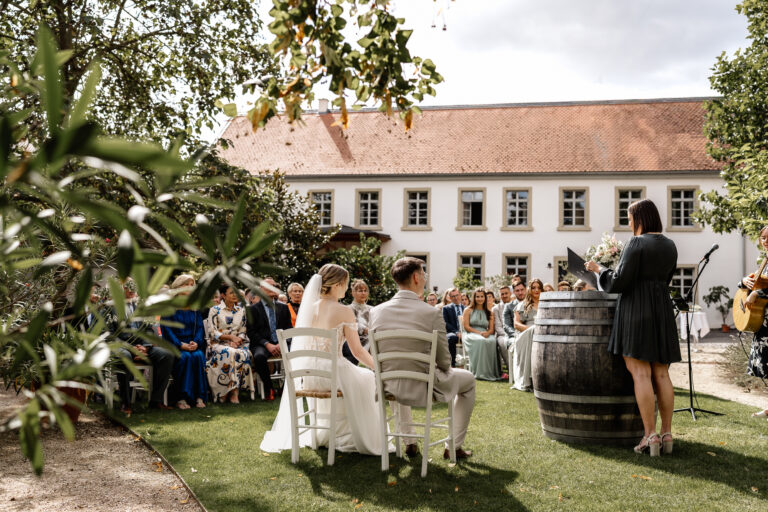 Freie Trauung im Garten, Brautpaar sitzt vor den Gästen während der Zeremonie