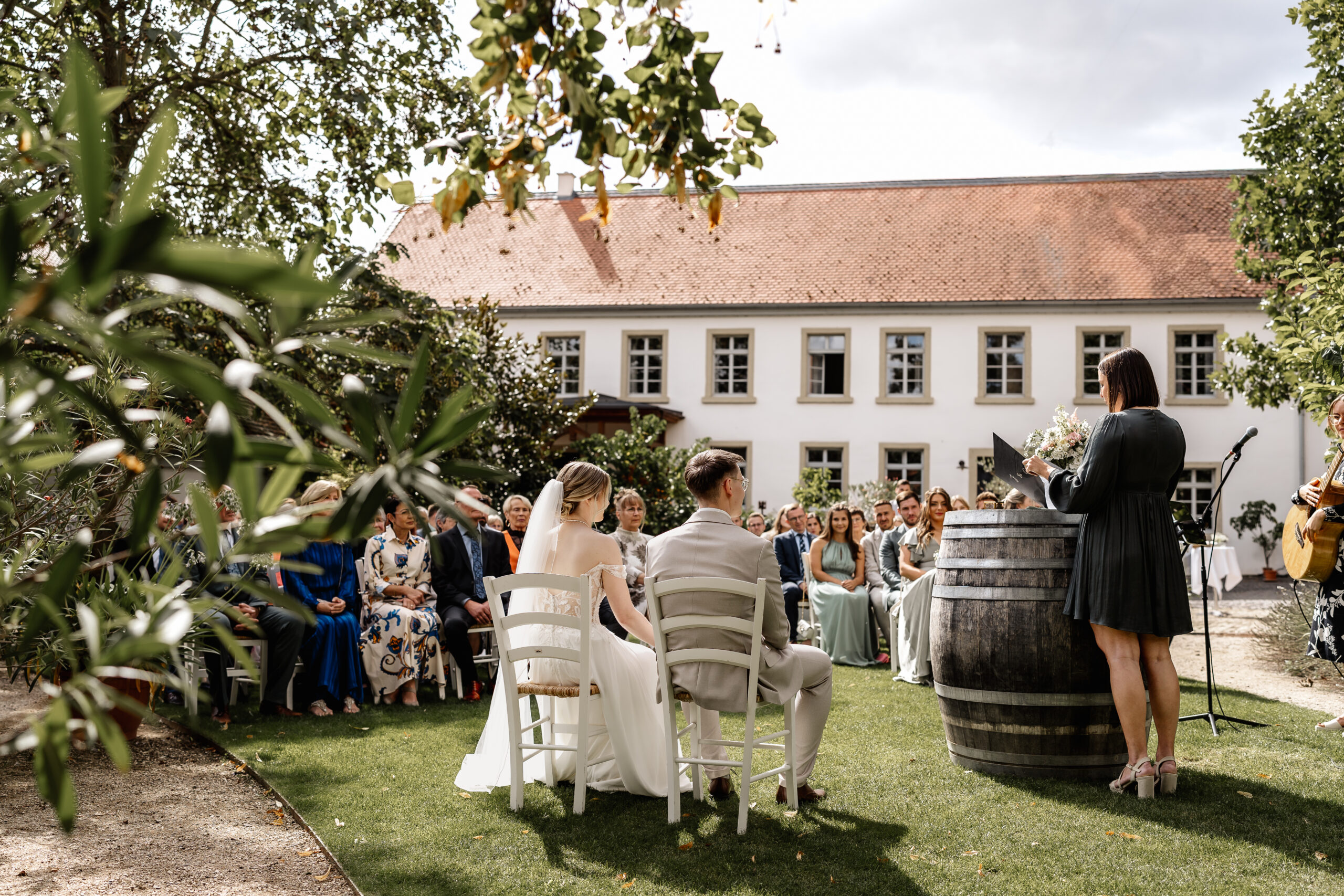 Freie Trauung im Garten, Brautpaar sitzt vor den Gästen während der Zeremonie