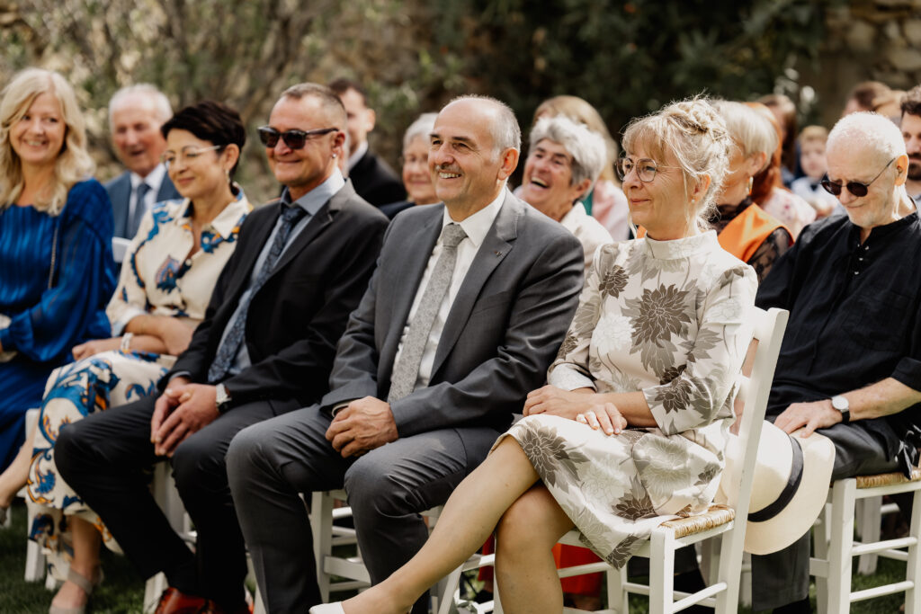 Hochzeitsgäste sitzen lächelnd während der Trauung,