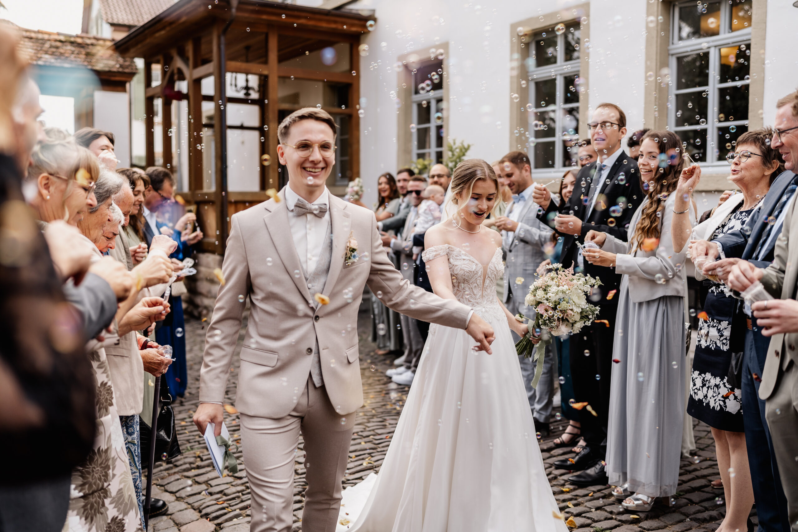 Hochzeitspaar läuft durch Seifenblasen Spalier im Innenhof von Eventlocation BourdierKoeller