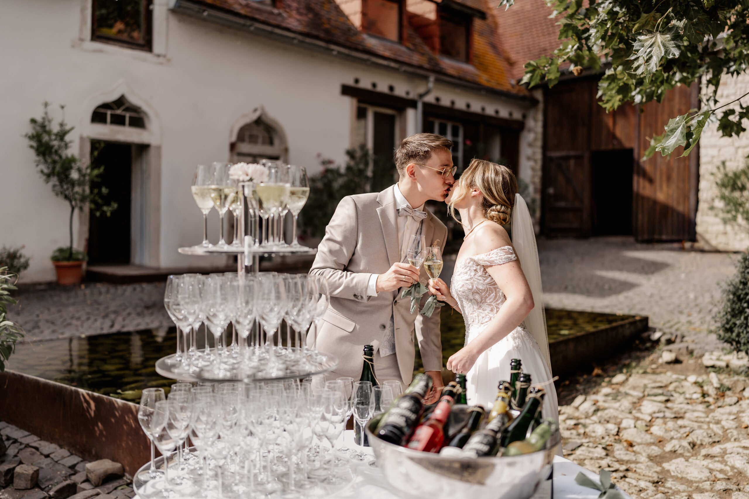 Brautpaar stößt mit Champagner an und küsst sich innig