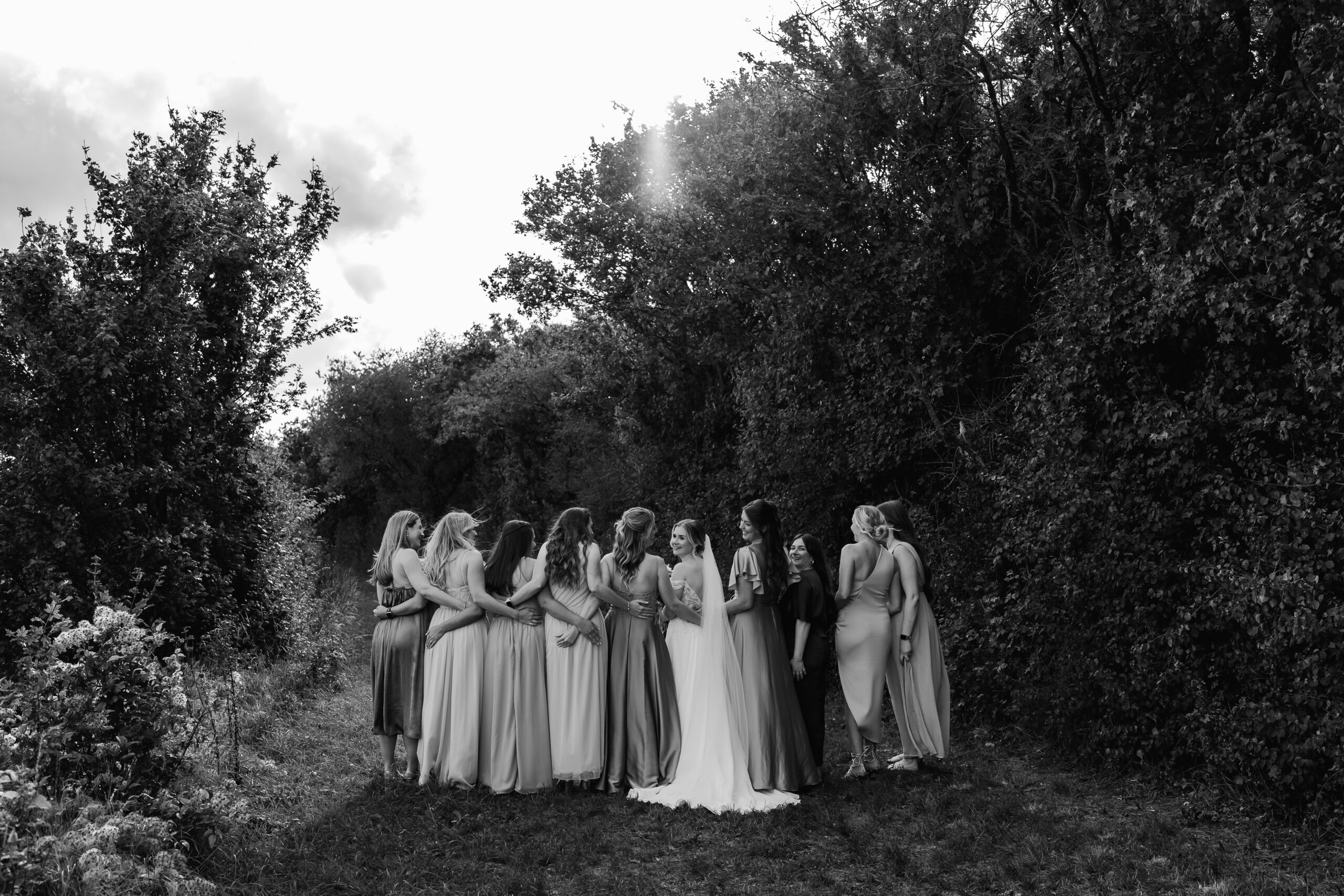 Schwarzweißfoto der Braut mit Brautjungfern von hinten, künstlerische Hochzeitsfotografie