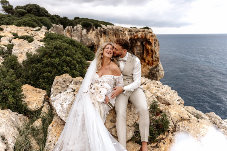 Brautpaar kuschelt bei After-Wedding-Shooting mit Blick auf Meer und Klippen Mallorca