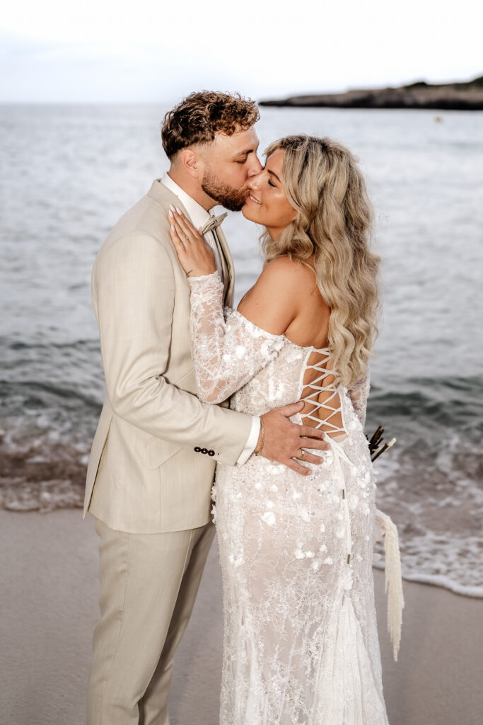 After-Wedding-Shooting am Strand auf Mallorca mit Brautpaar am Meer, Brautpaar küsst sich liebevoll