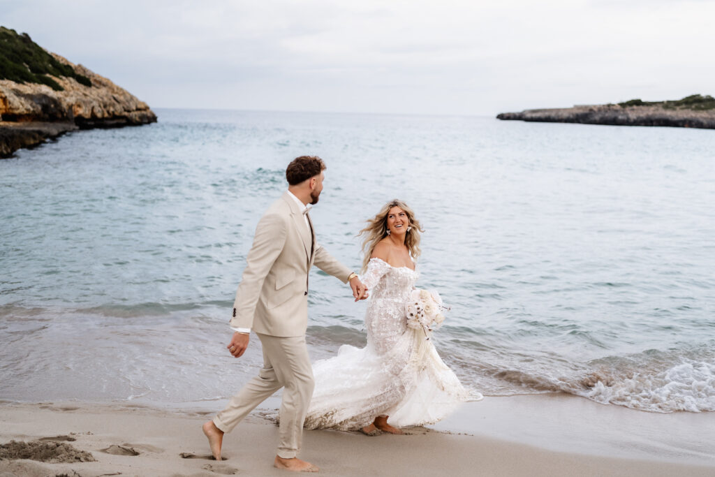 Strand - Fotosession auf Mallorca mit Brautpaar barfuß im Sand und dem Meer in Hintergrund
