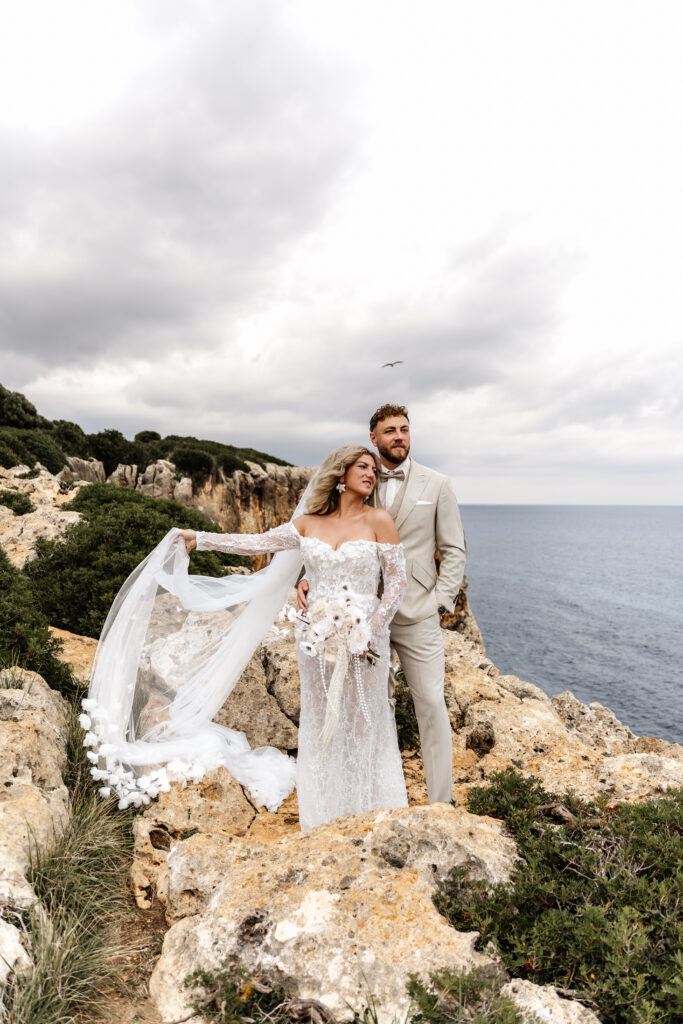Brautkleid fließt im Wind bei After-Wedding-Shooting auf Felsen Mallorca