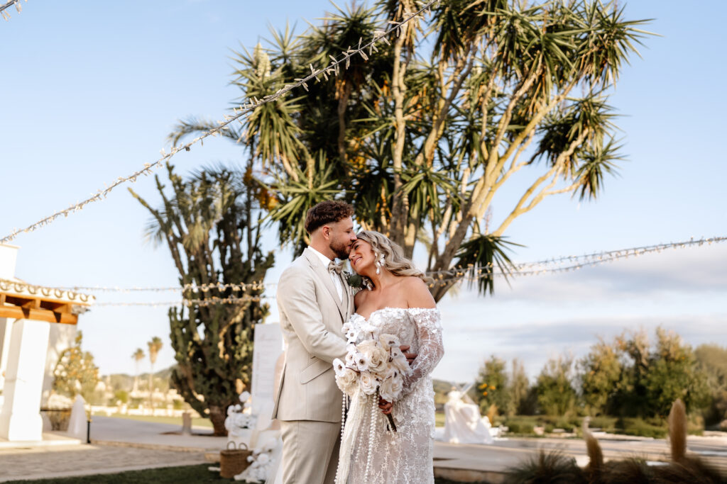 Brautpaar kuschelt vor einer Palme auf der Hochzeitslocation auf Mallorca