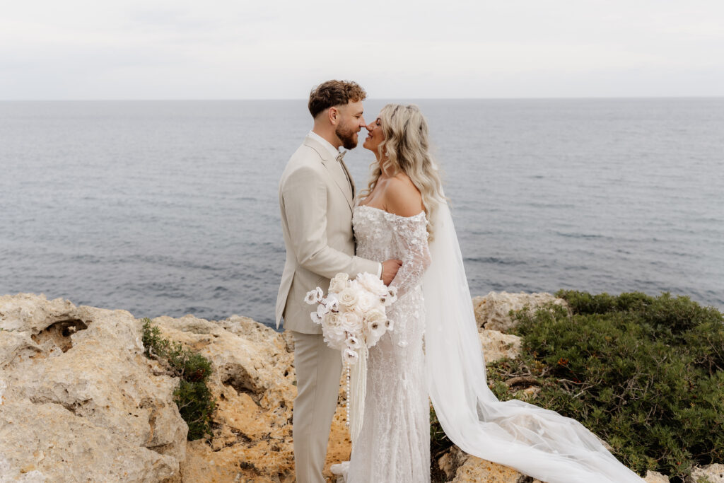 Brautpaar steht bei After-Wedding-Shooting auf Felsen an Mallorcas Küste