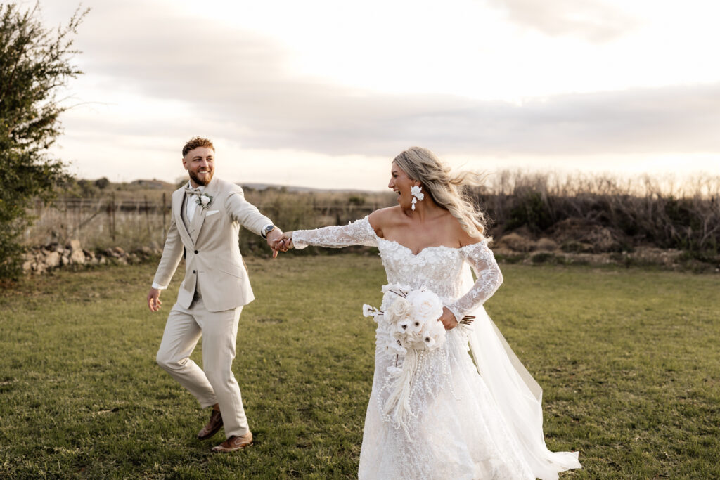 Brautpaar rennt lachend über die Wiese beim Sonnenuntergang im Vino Resort Son Amaret auf Mallorca