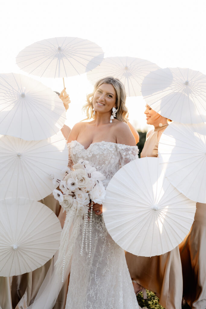 Brautjungfern umrahmen die Braut mit Sonnenschirmen beim Sonnenuntergang auf Mallorca