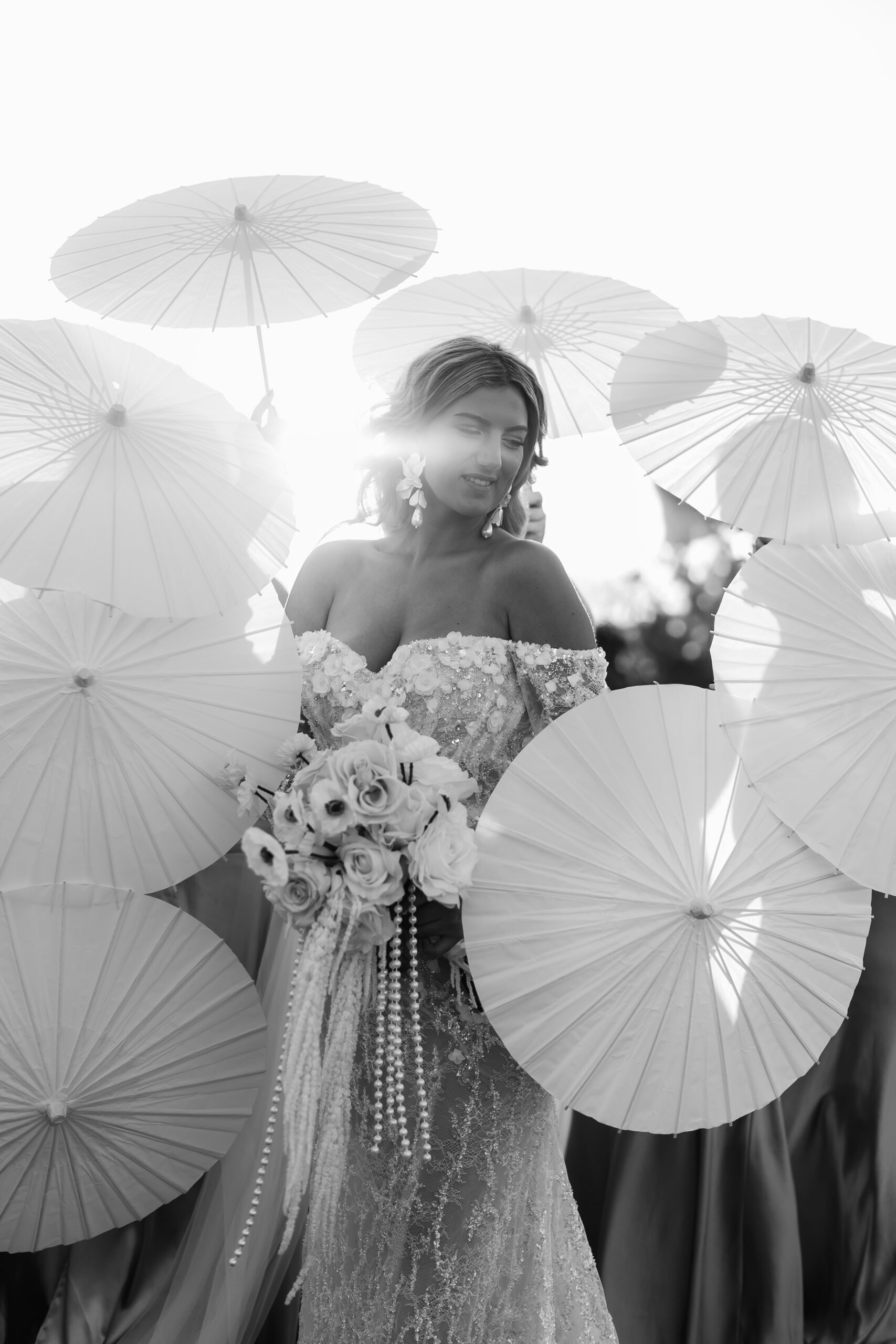Schwarz-Weiß Bild Braut im Mittelpunkt mit Brautjungfern und Sonnenschirmen zur Golden Hour