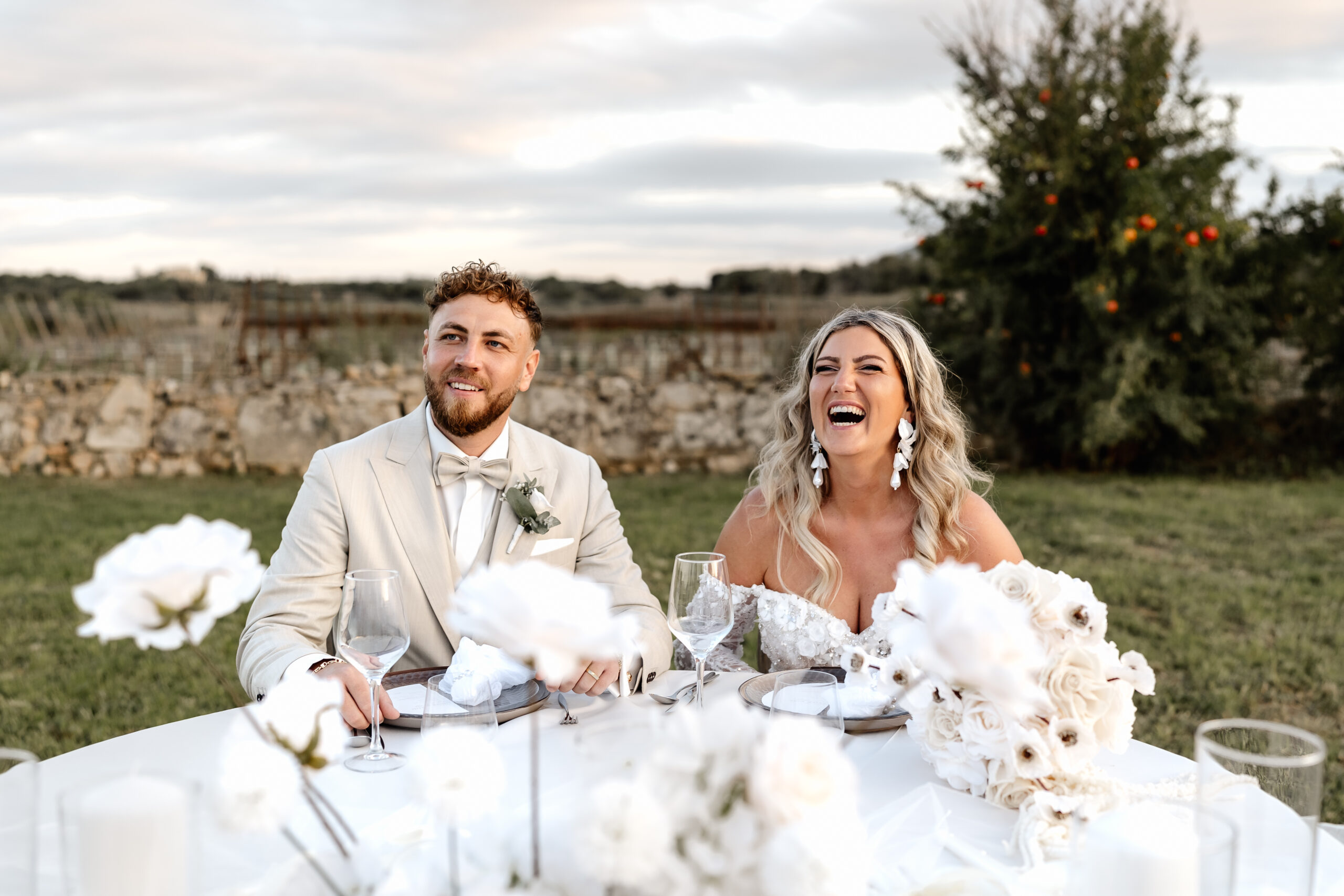 Brautpaar sitzt lachend am Tisch in der Hochzeitslocation Mallorca